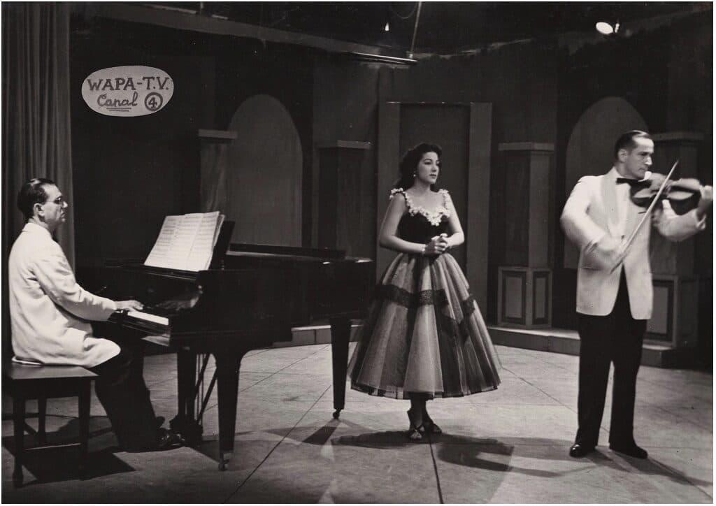 José Enrique Pedreira al piano y Henry Hutchinson, Sr. al violín mientras Olga Iglesias canta para la televisión WAPA a fines de la década de 1950.