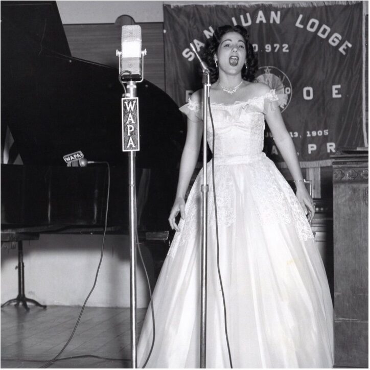 Olga Iglesias cantando para una logia local de San Juan alrededor de fines de la década de 1950 mientras se transmitía en la radio WAPA.